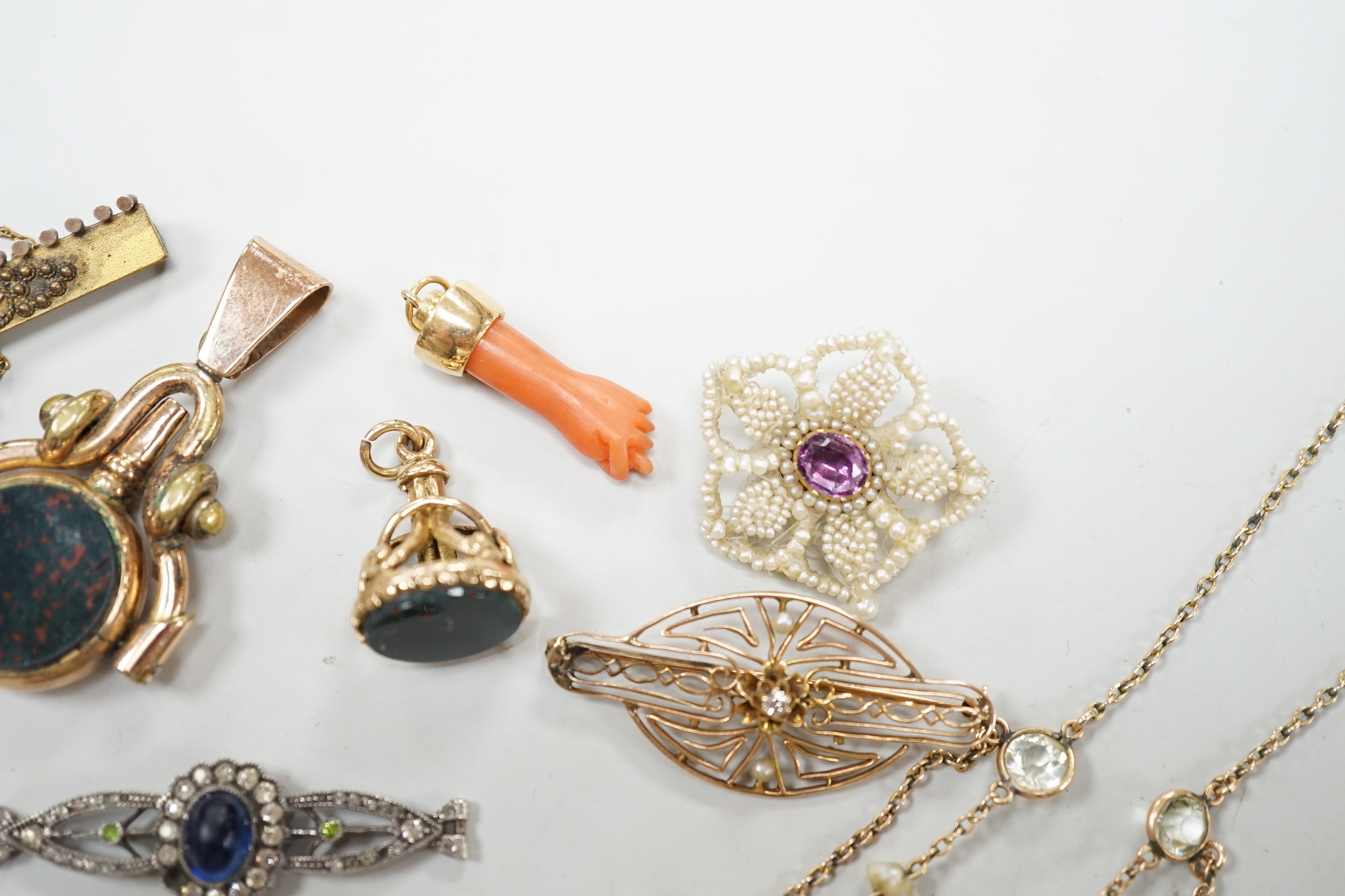 A small group of antique and later jewellery, including 9ct gold and bloodstone fob seal, a 1930's yellow metal and seed pearl set key brooch, 14k and black enamel brooch, spinning fob pendant, coral hand charm, 10k and